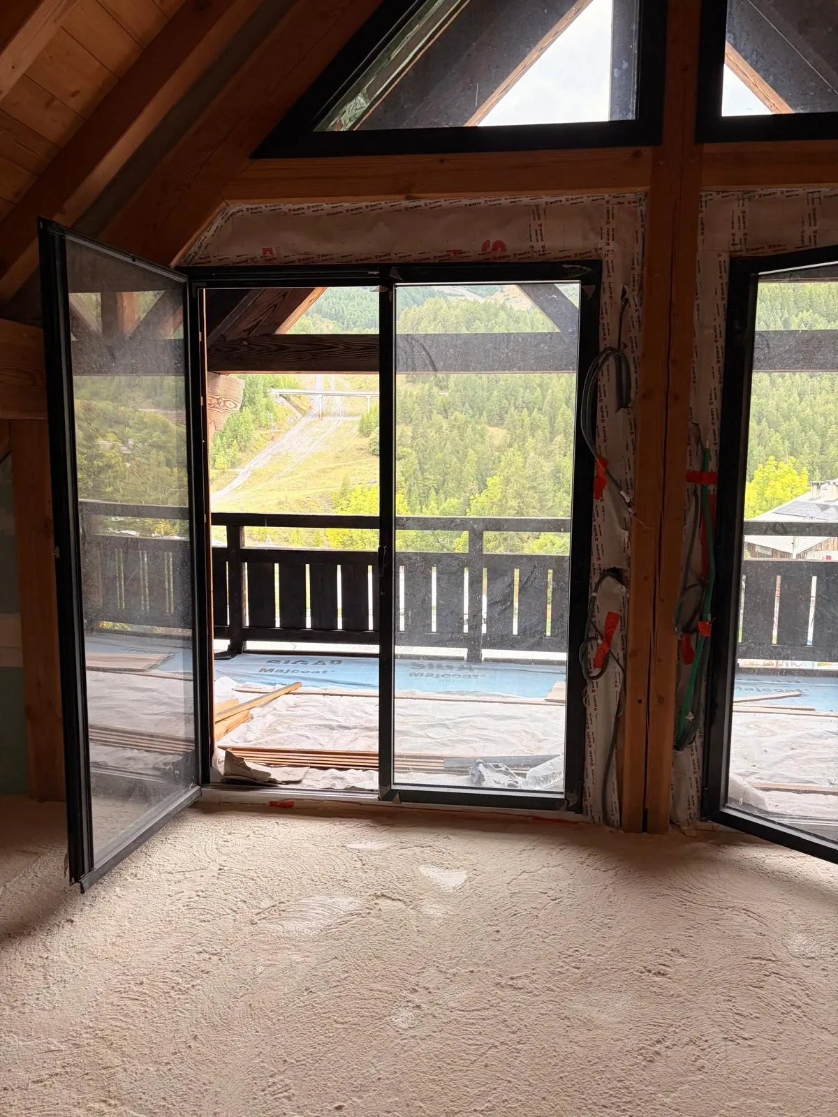 Sol isolé devant une grande baie sous charpente — chantier à Auron